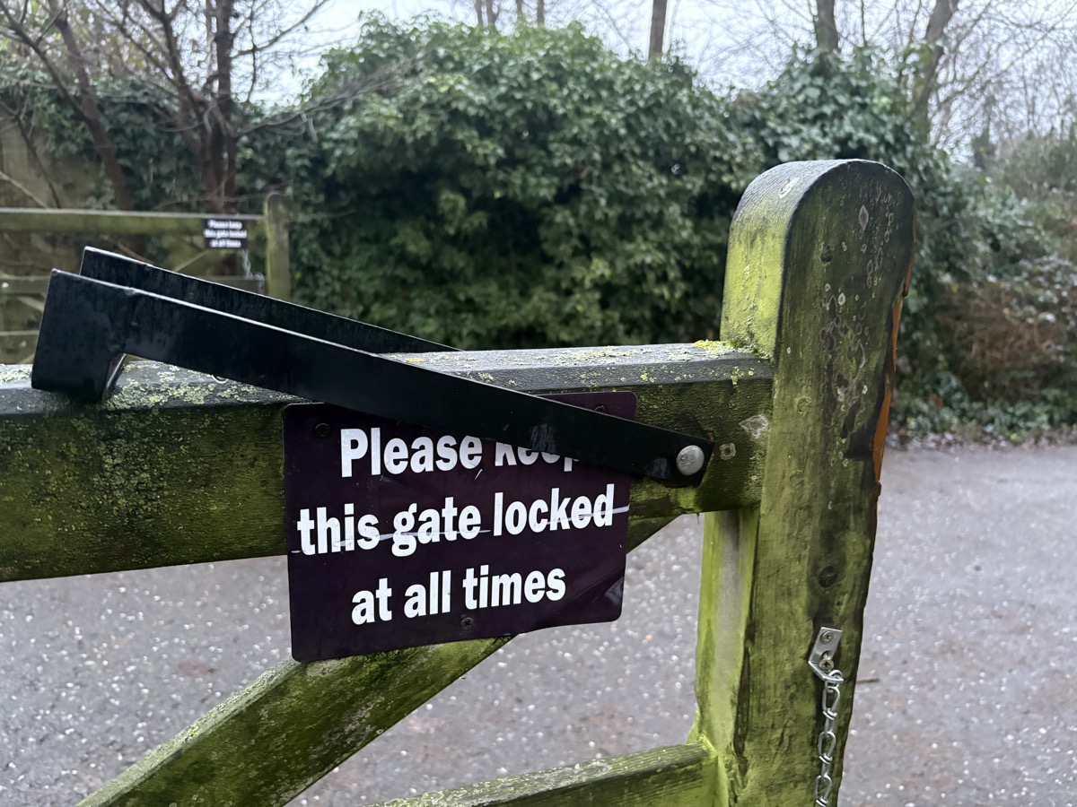 Open gate with sign saying keep it locked